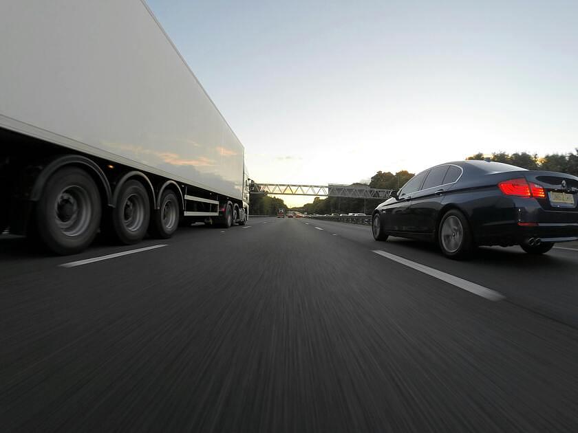 vrachtwagen op snelweg naast auto